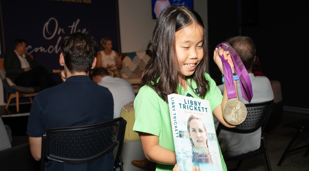 Young girl holding Libby Trickett's book and gold medal