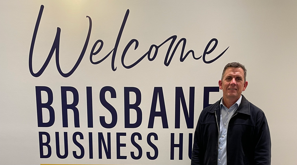 Andrew Chamberlin with the welcome to brisbane business hub sign